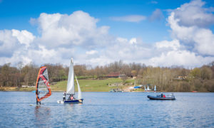 Things to do at Bewl water during summer. Sailing boats and windsurfing on a blue sunny day