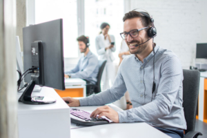Man speaking on a headset at a computer