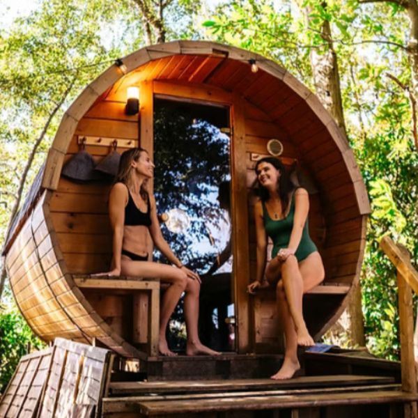 two people sitting outside a sauna in the forest