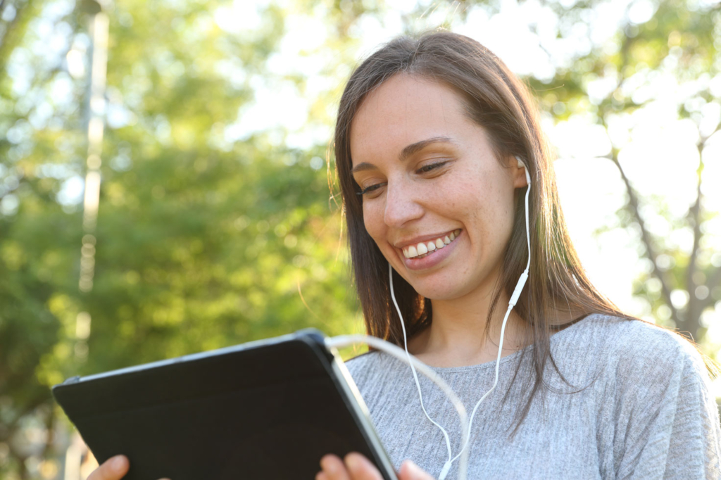 Woman with earphones listening to the audio trail on her tablet Woman with earphones listening to the audio trail on her tablet
