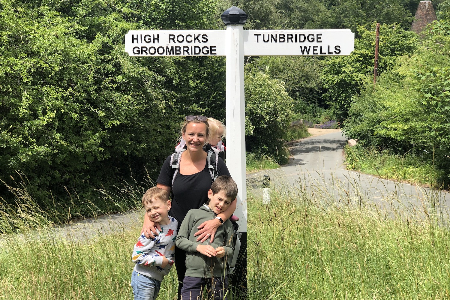 The High Rocks A woman with her three children standing in front of a sign post pointing towards Tunbridge Wells on the right and High Rocks Groombridge on the left