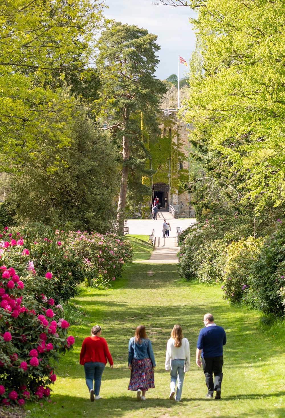hever-castle-gardens A group of people walking down a pathway leading towards Hever Castle