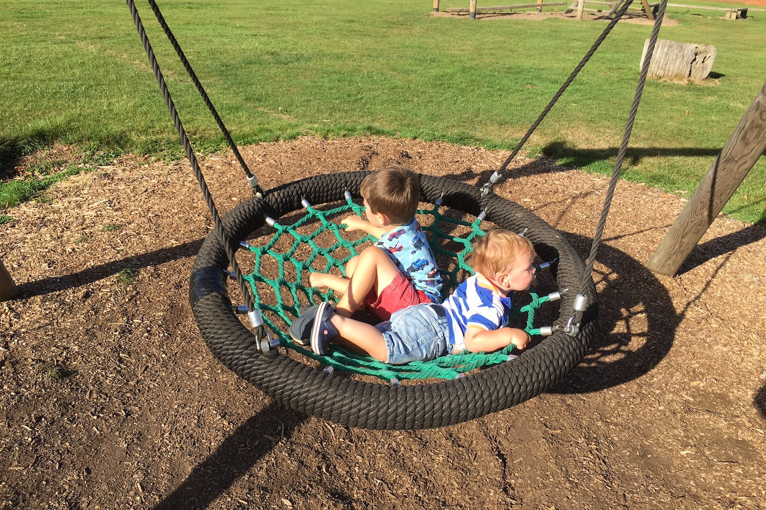 penshurst-place-8 Two young children sat on a basket swing in a park