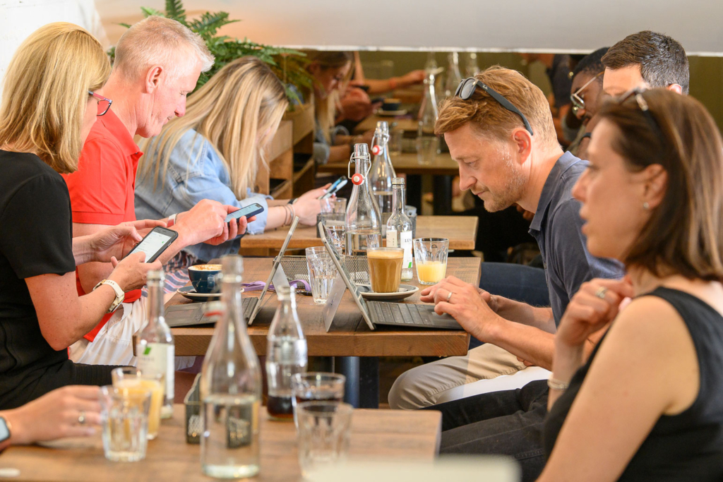 working-at-StKilda A range of people sat at a few tables in a coffee shop, working and enjoying their coffee