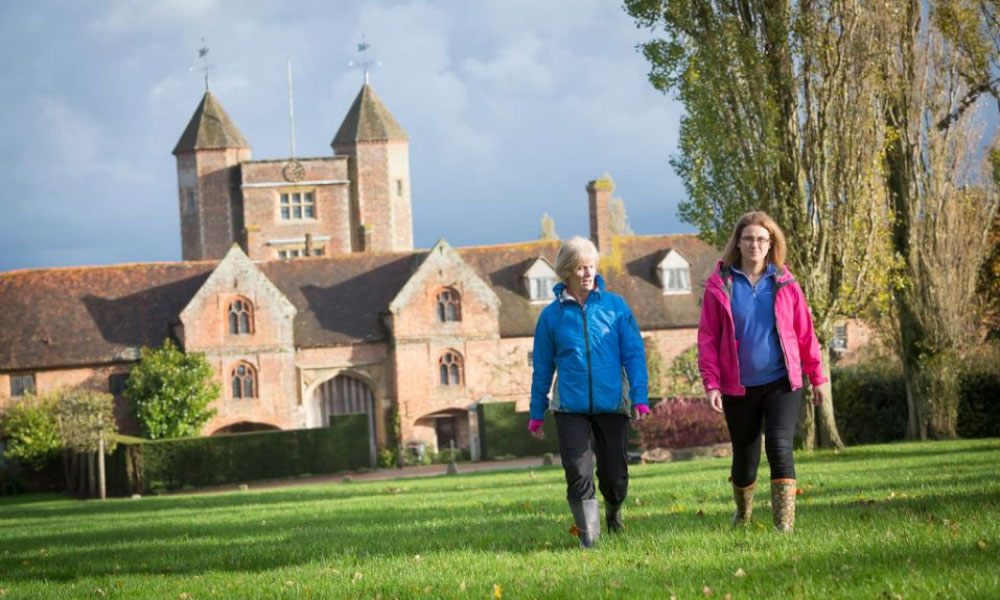 Image of Sissinghurst Castle and people walking through a field Image of Sissinghurst Castle and people walking through a field