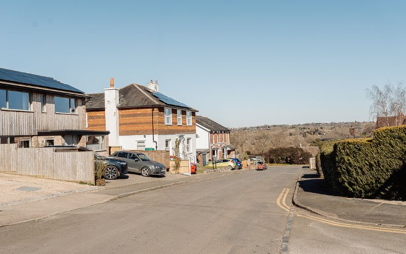 View of street going downhill, modern and Victorian properties on the left hand side of the road