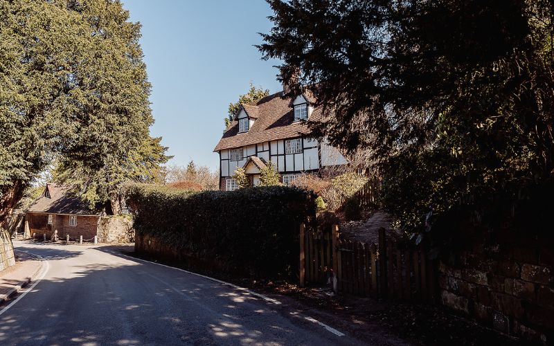 Tudor house with hedge in front of it