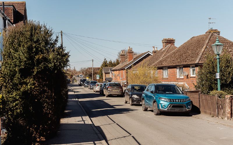 Village street with parked cars on the right