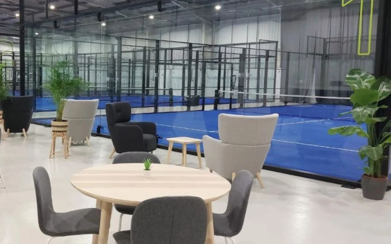 Interior of indoor Padel center with cafe seating in foreground